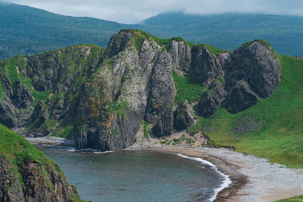 Coastal landscape wild bay with sandy beach between basalt rocks