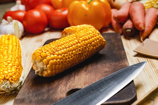 Cobs of corn on wooden cutting board on table