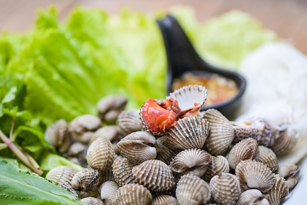 Cockle shellfish seafood plate with fresh vegetable herbs and spices on plate food Cockles background blood cockle peeled on table with seafood sauce