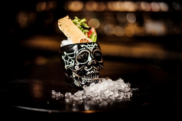 Cocktail in the black skull cup in mexican style with fruits