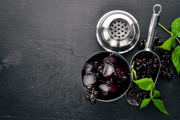 Cocktail of fresh black currant with ice on a wooden background Top view Free space