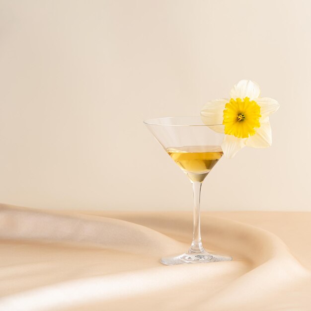 Cocktail glass with a flower set on pink wavy satin in front of a pink background