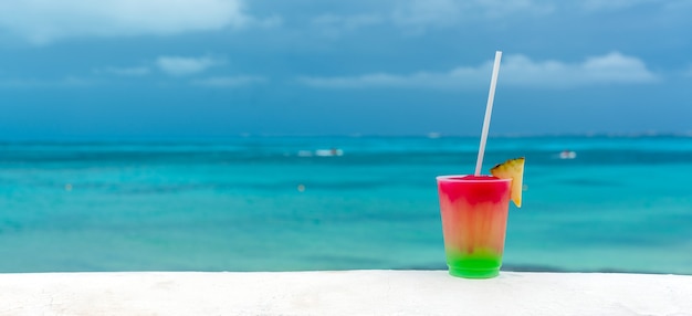 Cocktail with caribbean sea on background concept of beautiful tropical vacation