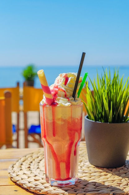 Cocktail with ice cream and fruit syrup on the beach