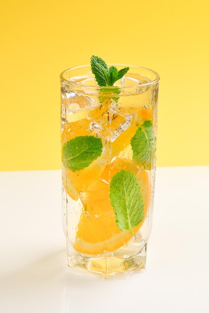 Cocktail with lemon and mint on a yellow background Copy space