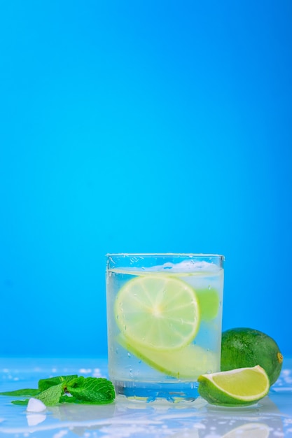 Cocktail with lime and fresh mint in glass on a blue background