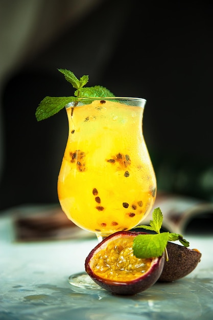 Cocktail with mango and passion fruit in a glass next to passion fruit halves