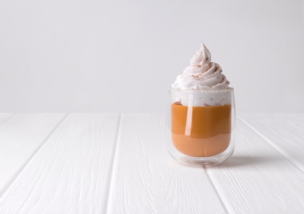 Cocktail with whipped cream on top on white wooden background