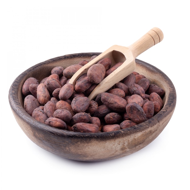 Cocoa fruit in a wooden bowl, raw cacao beans isolated on a white background