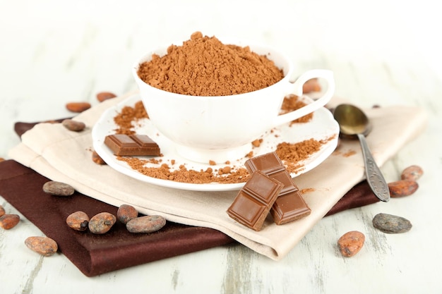 Cocoa powder in cup on napkin on wooden table