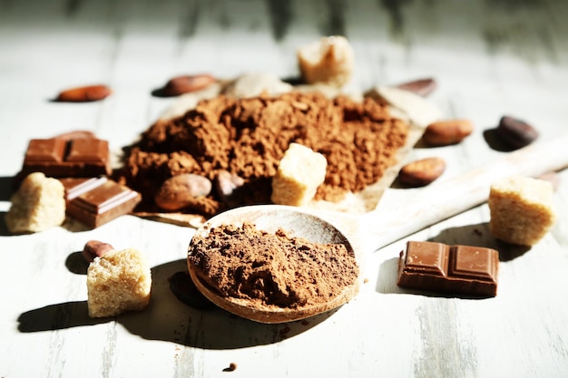 Cocoa powder in spoon on wooden table