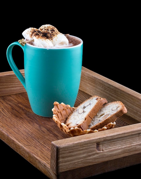 Cocoa with marshmallow on a wooden board with almond crackers on a dark background