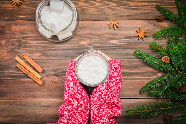 Cocoa with marshmallows in the hands of a wooden background