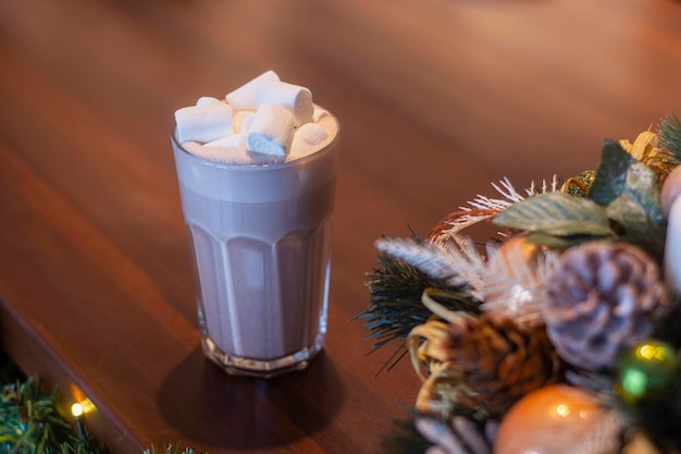 Cocoa with marshmallows in a transparent glass in a coffee shop on the background of New Year's decoration.