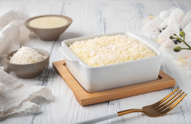 Coconut cake in a ceramic bowl on a white wooden table