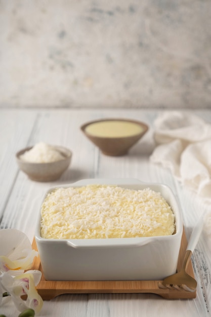 Coconut cake in a ceramic bowl on a white wooden table