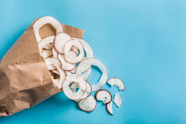 Coconut chips in a paper Kraft bag on a blue 