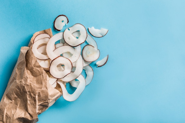 Coconut chips in a paper Kraft bag on a blue 