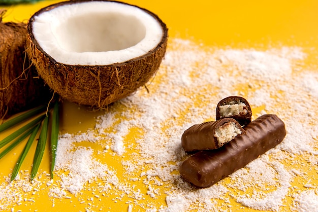 Coconut chocolate and shredded coconut on yellow background