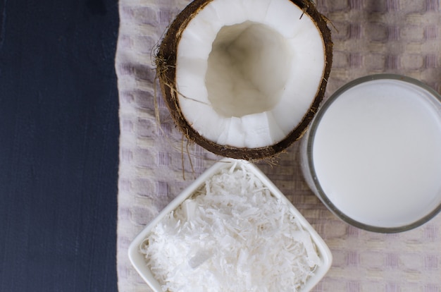 Coconut, coconut shavings and coconut milk on a black background.