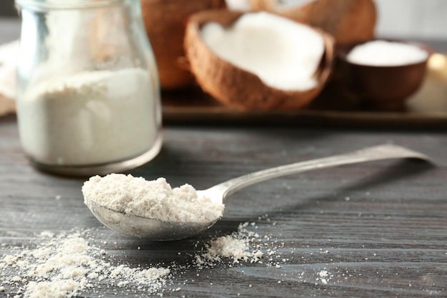 Coconut flour in metal spoon against blurred background