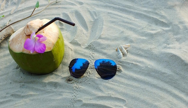 Photo coconut fruit and sunglasses on the sandy beach