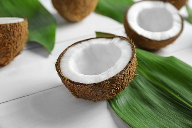 Coconut half with green leaf on wooden background