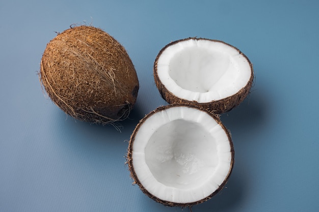 Coconut halves, coconut pieces set, on blue textured summer background