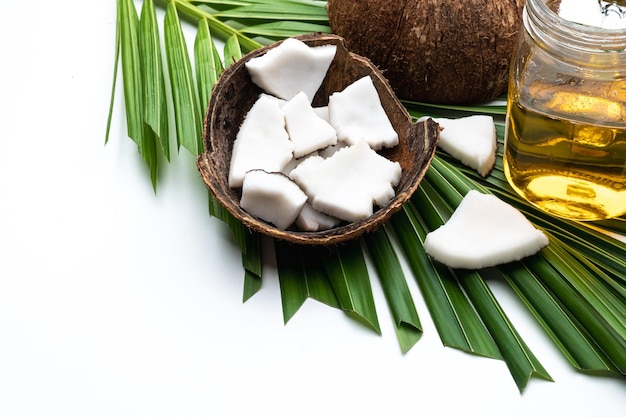 Coconut meat and coconut oil in glass bottle on coconut leaf