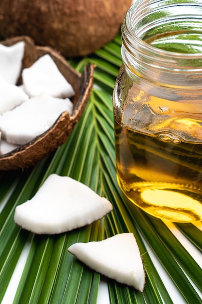 Coconut meat and coconut oil in glass bottle on coconut leaf