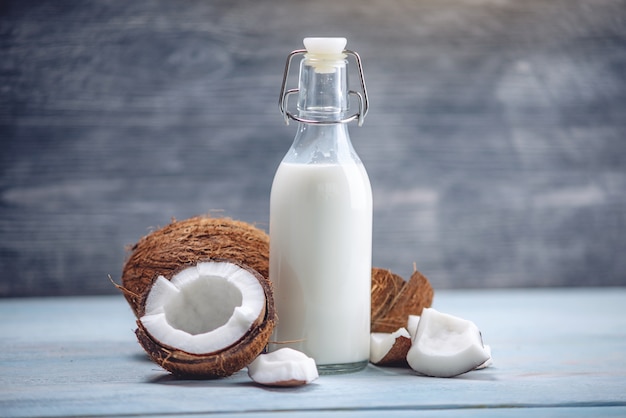 Coconut milk in a bottle in a composition with an open coconut with white flesh