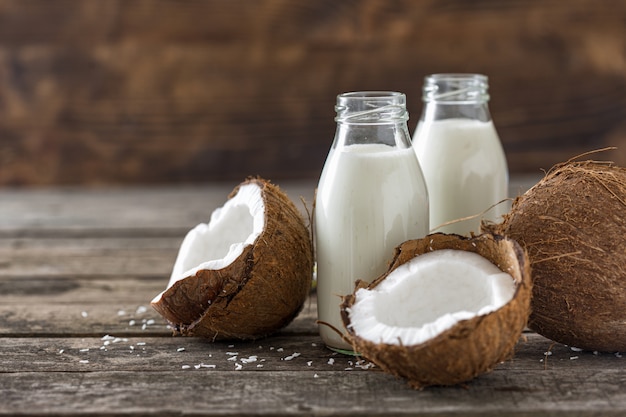 Coconut milk in bottles on wooden table. Vegan non dairy healthy drink. Healthy eating concept