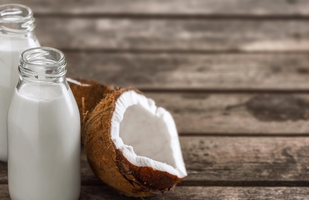 Coconut milk in bottles on wooden table with copy space.  Healthy eating concept