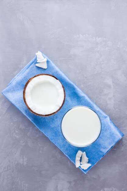 Coconut milk and coconut in glass on gray background Coconut vegan milk non dairy on blue napkin