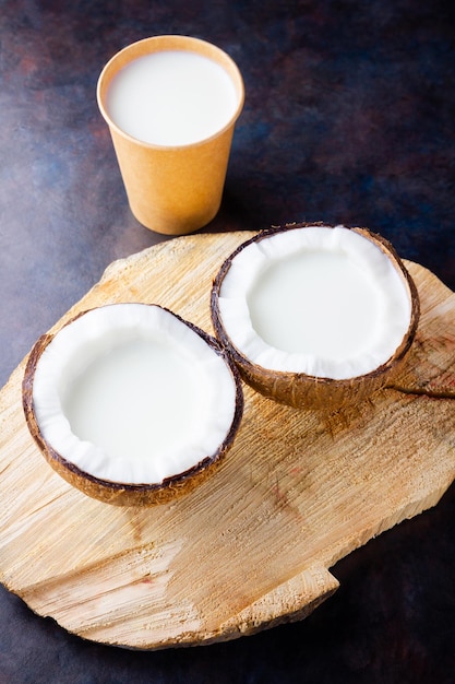 Coconut milk and coconut in paper glass on dark background Coconut vegan milk non dairy