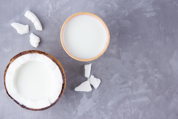 Coconut milk and coconut in paper glass on gray background Coconut vegan milk non dairy