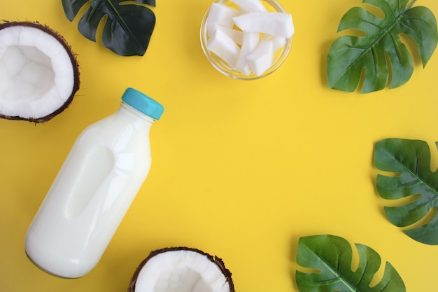 Coconut  milk in the glass bottle on the  yellow background.Top view.Copy space.