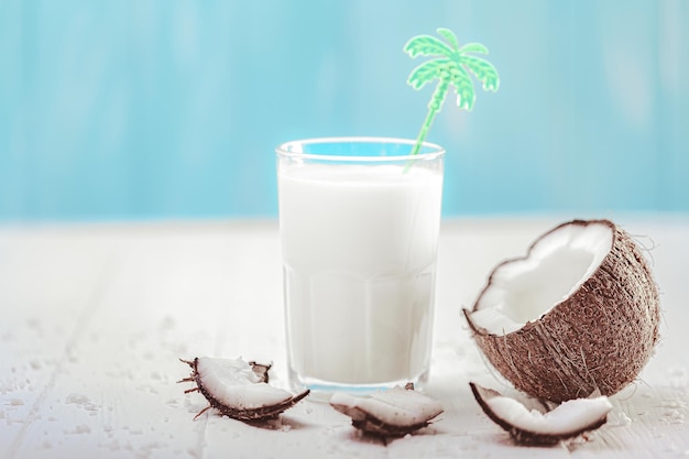 Coconut milk in glass with coconut fruit on wooden table Alternative milk concept Tropical drink