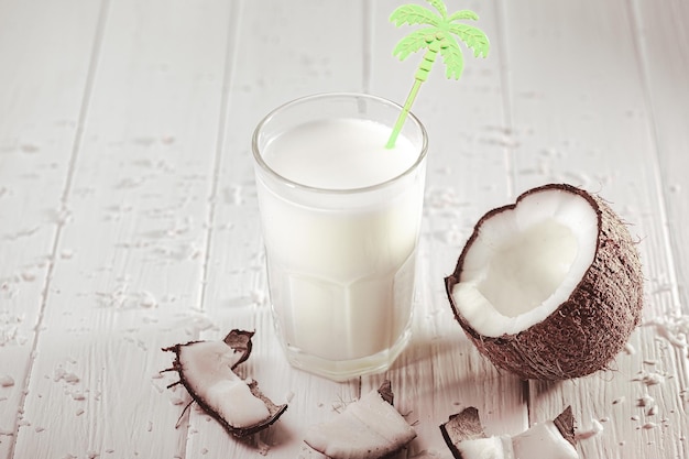 Coconut milk in glass with coconut fruit on wooden table Alternative milk concept Tropical drink