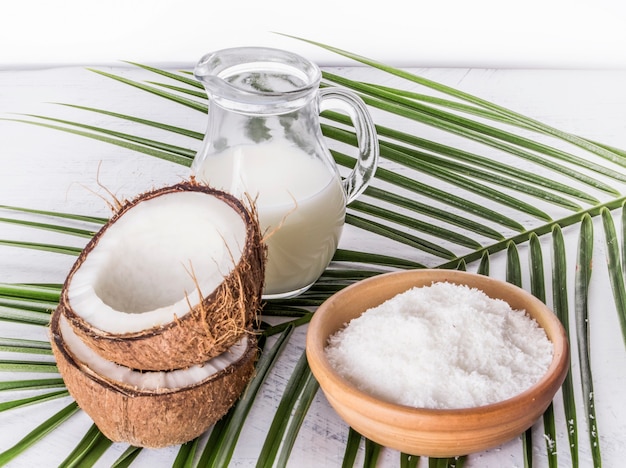 Coconut milk with coconut shavings and broken coconut on palm leaf.