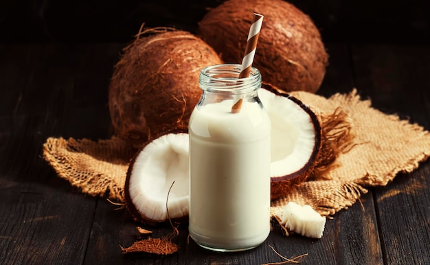 Coconut non dairy milk in glass bottle dark kitchen table background chocolate tint selective focus