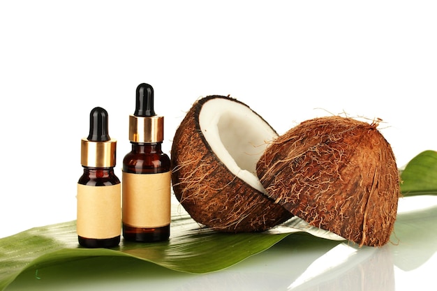 Coconut oil in bottles with coconuts on white background