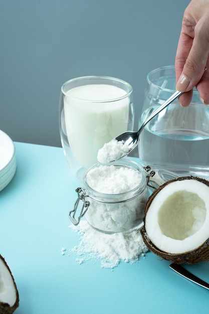 Coconut products cracked open coconut with meat cut in half coconut powder in a glass jar plant milk