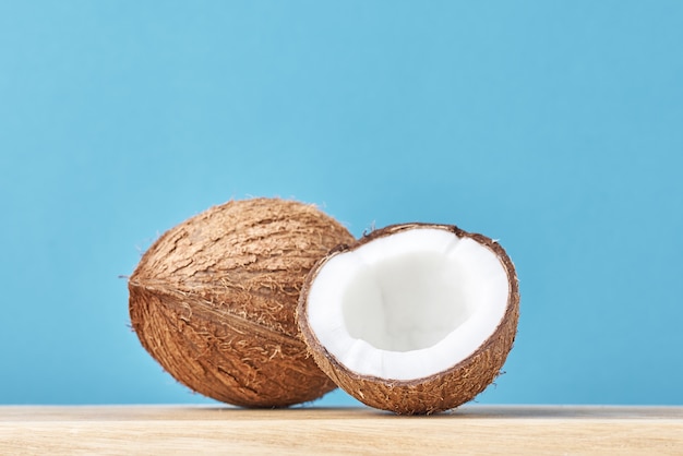 Coconut with half on wooden table against blue background