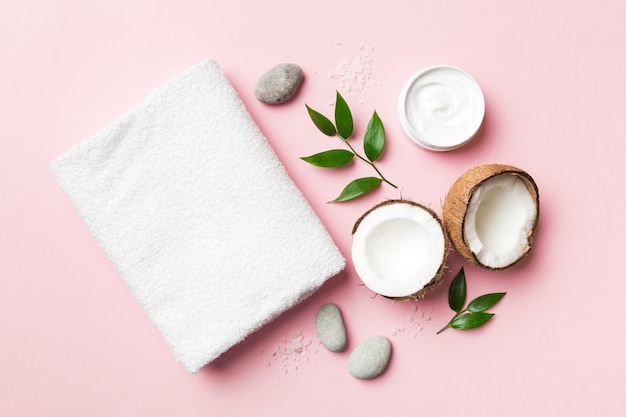 Coconut with jars of coconut oil and cosmetic cream on colored background Top view Free space for your text Natural spa coconut cosmetics and organic treatment concept Coconut Spa composition