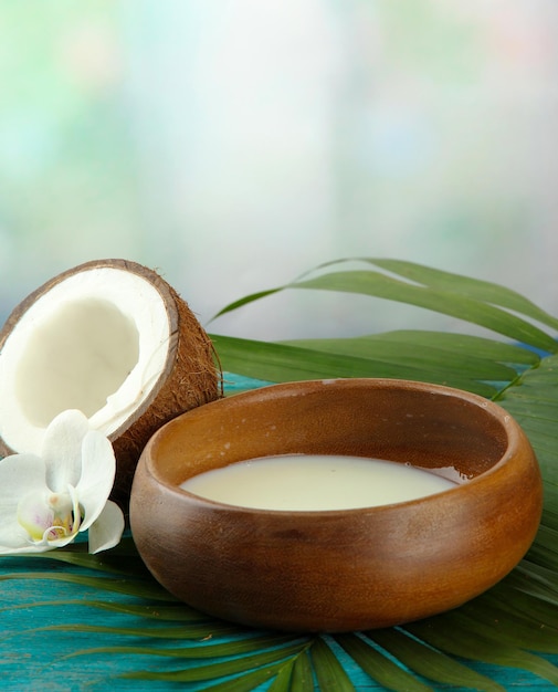 Coconut with leaves and flower on blue wooden background