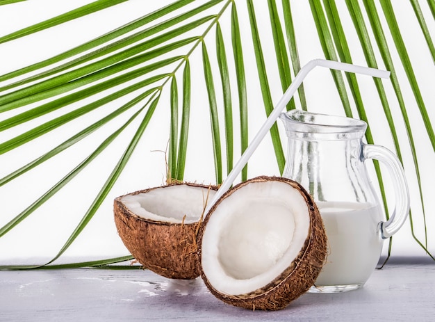 Coconut with a white drinking tube and a jug of coconut milk.