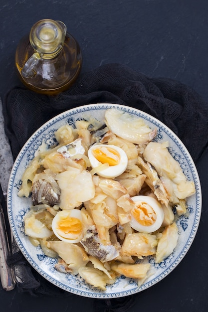 Cod fish with onion, eggs and olive oil on dish