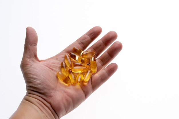 The cod liver oil capsules on a hand isolated on white background. 