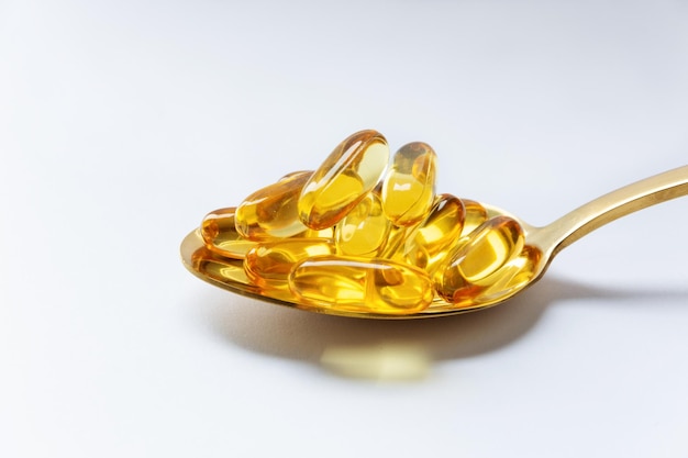 Cod liver oil omega 3 gel capsules on a spoon on white background